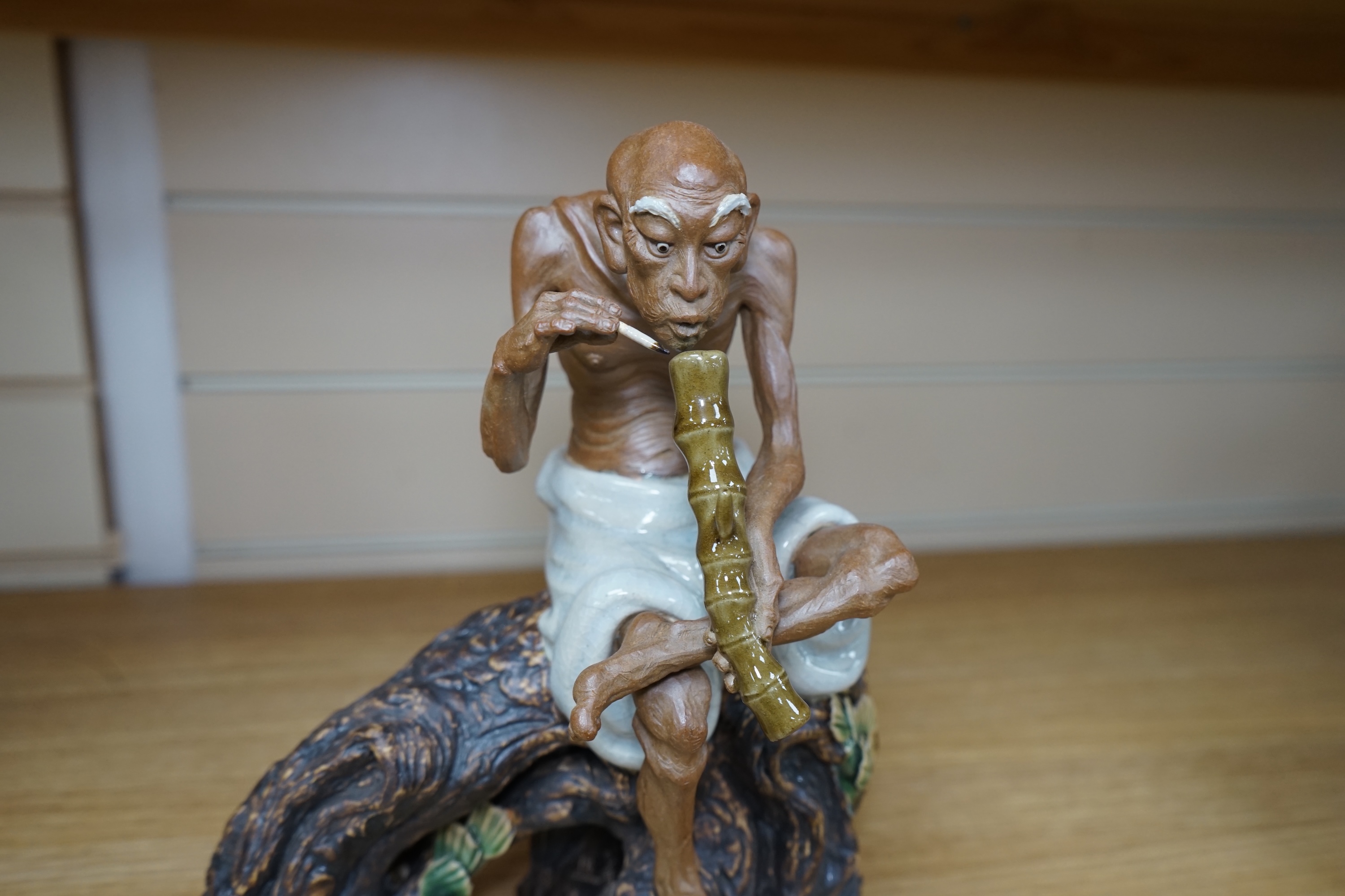 A 20th century Chinese figure of an opium smoker, maker’s seal to reverse and inscribed to interior base, 25cm. Condition - good